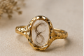 Le Rosse Studio gold botanical relic ring preserving a delicate curl of baby hair in a clear oval heirloom setting