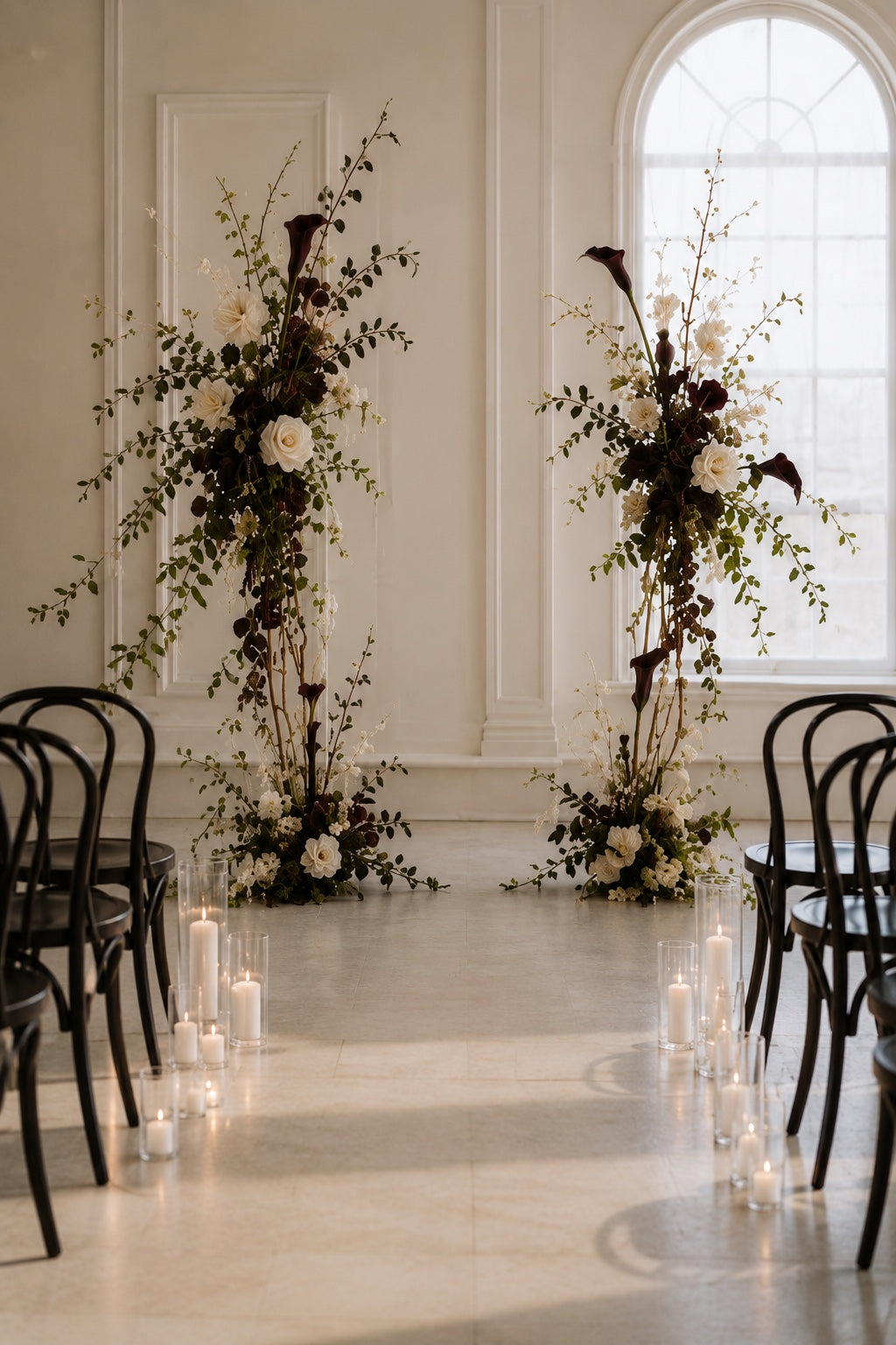 Le Rosse Studio sculptural floral rental installation with dark calla lilies, ivory flowers, burgundy accents, olive greenery, and candlelight