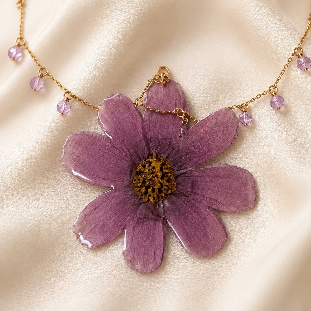 Close-up of purple preserved flower pendant with gold chain and crystal drops