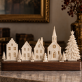 The Winter Village design preview showing ivory village buildings, trees and snowman on a display base.